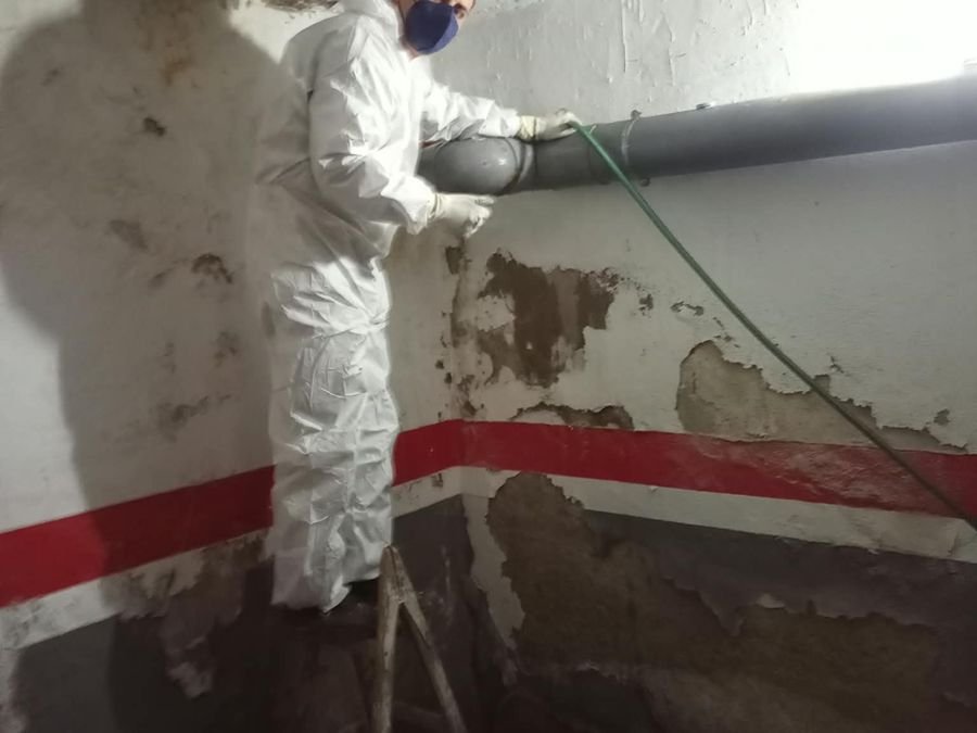 Michell con traje de protección trabajando en el sótano de una comunidad