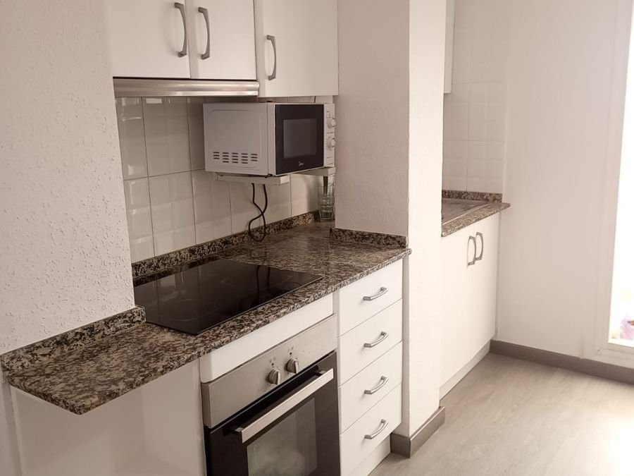 Cocina reformada con muebles blancos y encimera de granito